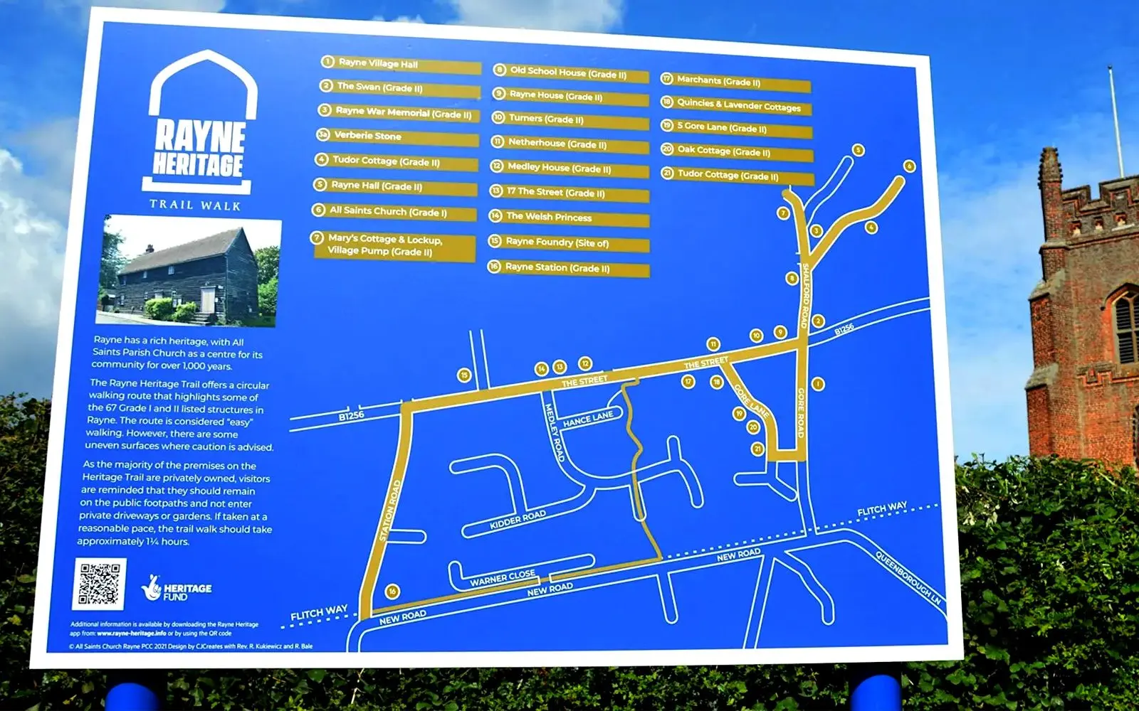 Rayne Heritage Trail map sign on a street in Rayne, Essex, with the village church tower behind