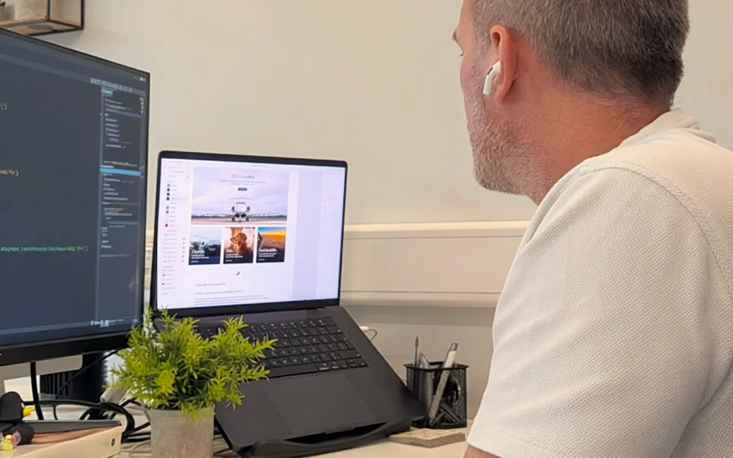 CJ Creates web designer building a client website at his desk in the Colchester studio, code on one screen and the live site on a laptop